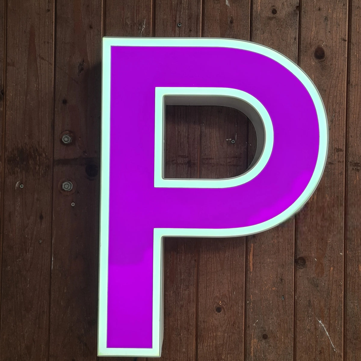 Paarse/witte vintage neonletter P op houten plank, met snoer.