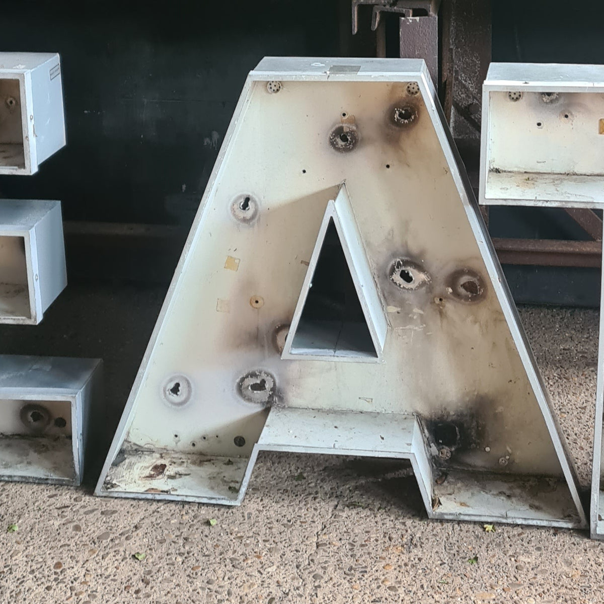 Robuuste aluminium letters EAT, vintage industriële uitstraling met roest- en slijtageplekken.
