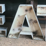 Robuuste aluminium letters EAT, vintage industriële uitstraling met roest- en slijtageplekken.
