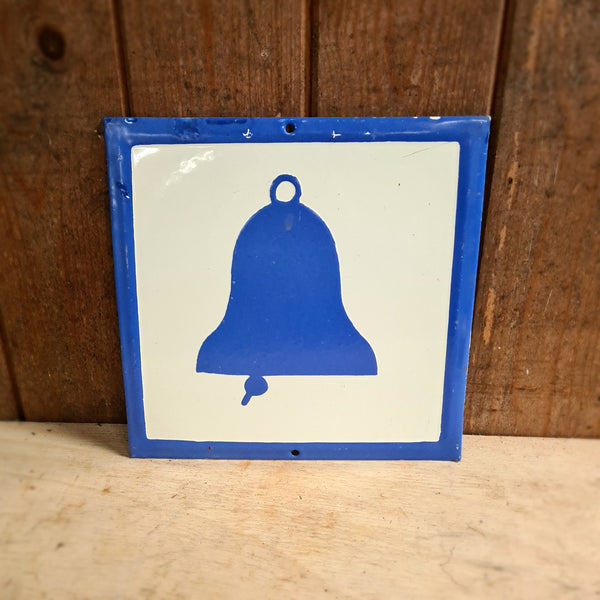 Emaille bord Bel met blauwe handbel silhouet, gebruikt voor fabriekswaarschuwingen, toont karakteristieke slijtage en patina, passend bij industriële vintage stijl van Heavy Stuff.