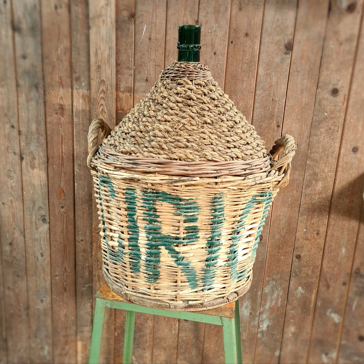 Oude gistfles met bedrukte mand, ambachtelijk en uniek decorstuk.
