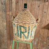 Oude gistfles met bedrukte mand, ambachtelijk en uniek decorstuk.