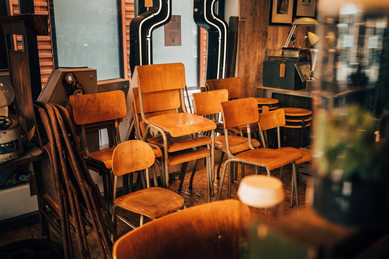 Authentieke industriële fabriekskrukken en robuuste vintage stoelen met zwaar stalen frame en geleefd hout