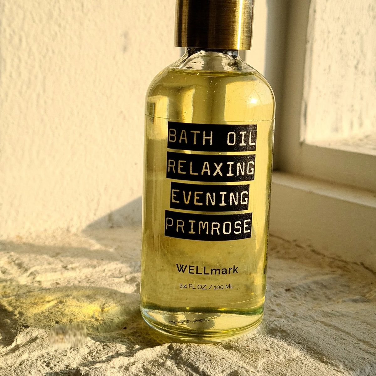 Huile de bain naturelle Wellmark à la formule nourrissante, posée sur le rebord de la fenêtre.