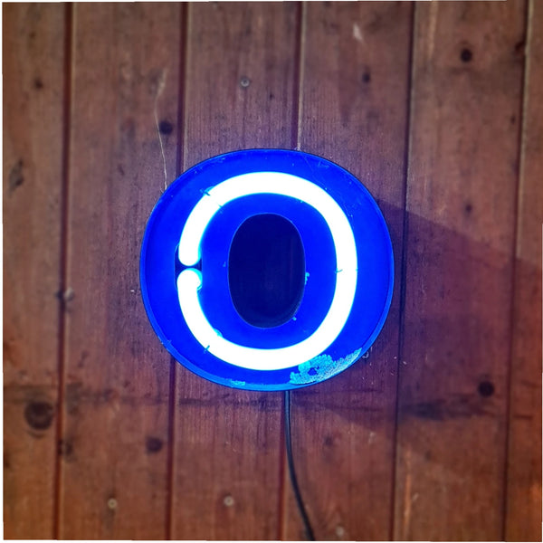 Klein formaat neonletter in blauw op houten muur, industriële verlichting - Heavy Stuff.