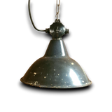 Close-up van de zware gietijzeren kop, ophangketting en nieuwe veilige bedrading van een originele industriële fabriekslamp.