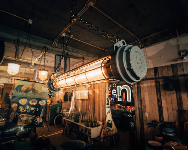 Grote vintage fabriekslamp hangend aan zware kettingen voor een industrieel interieur.